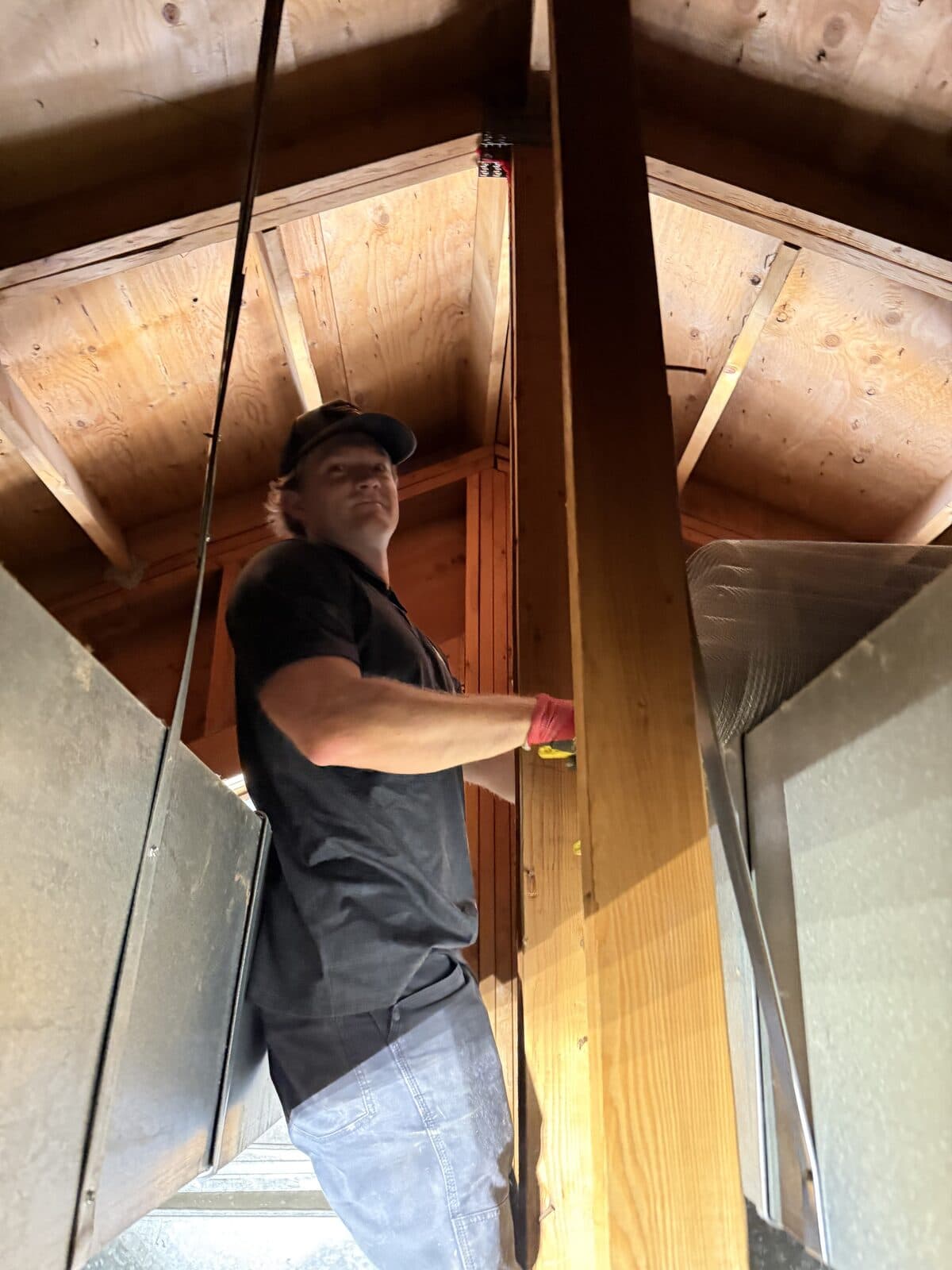 A technician inspecting an attic interior with a flashlight for signs of wildlife