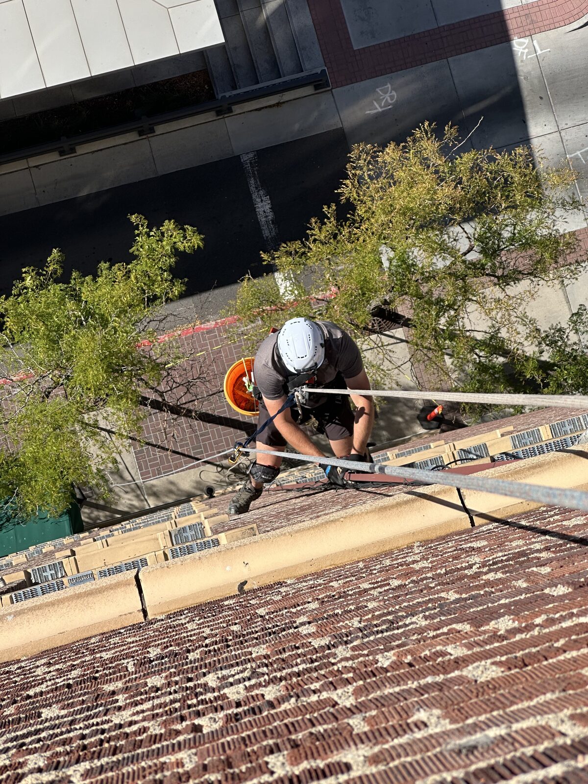 Technician descending a brick building above a downtown street
